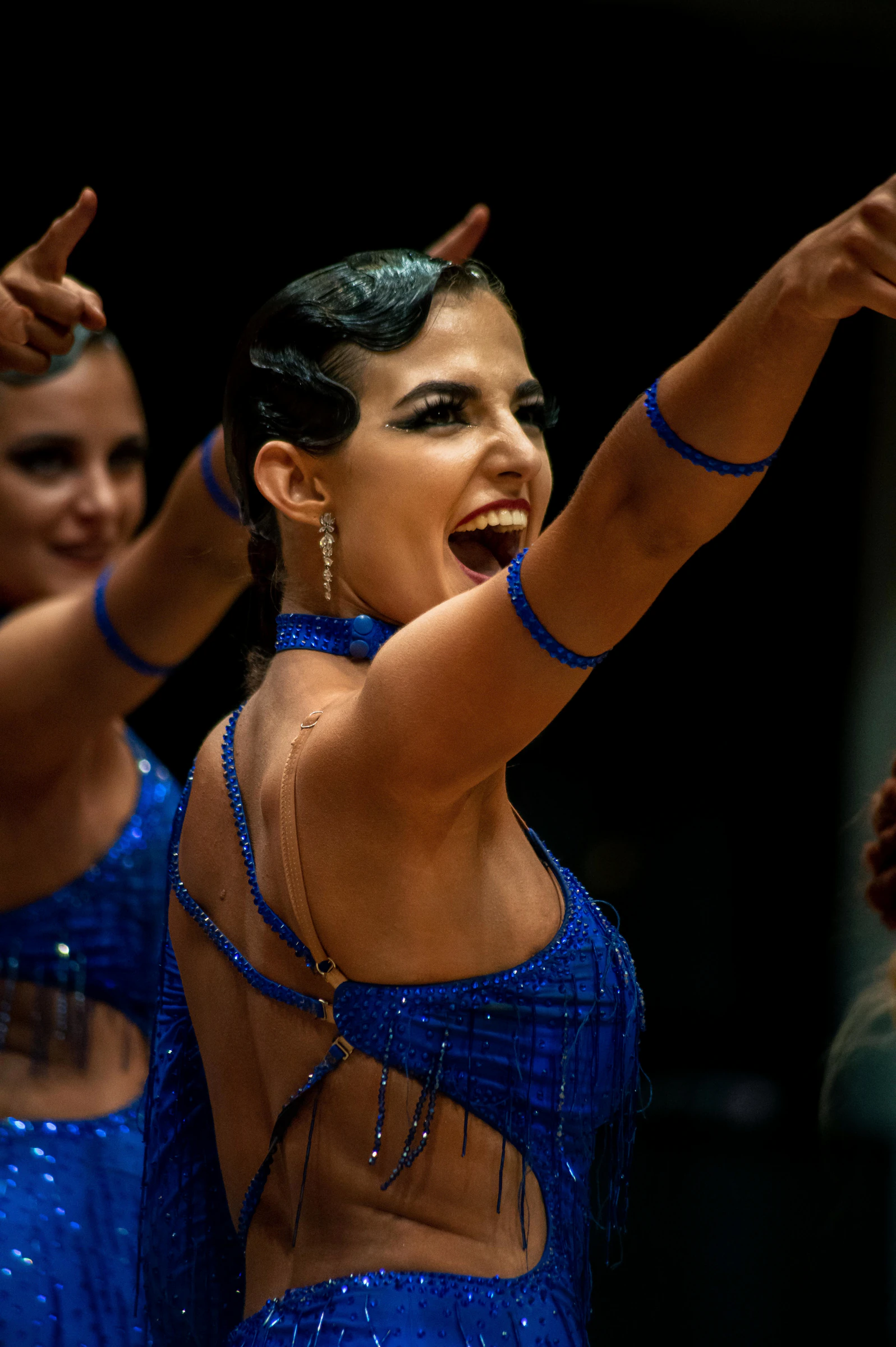 Eine Tänzerin in blauem Kostüm gestikuliert während einer energiegeladenen Darbietung.